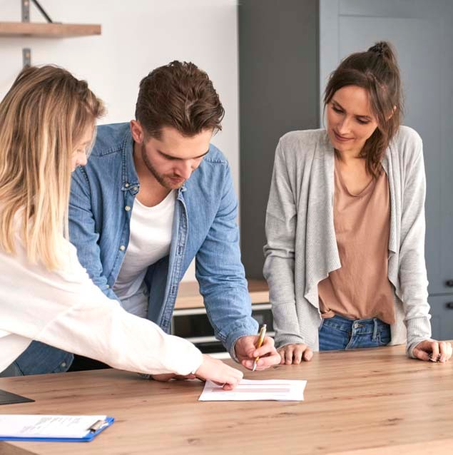 Young caucasian couple signing house purchase agreement with a real estate agent